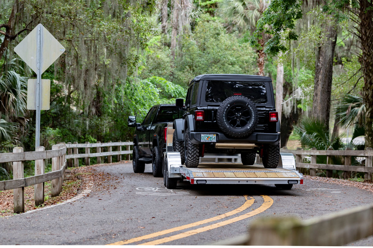 Black Jeep Loaded Onto Open Wood Deck Car Haulers On Paved Road