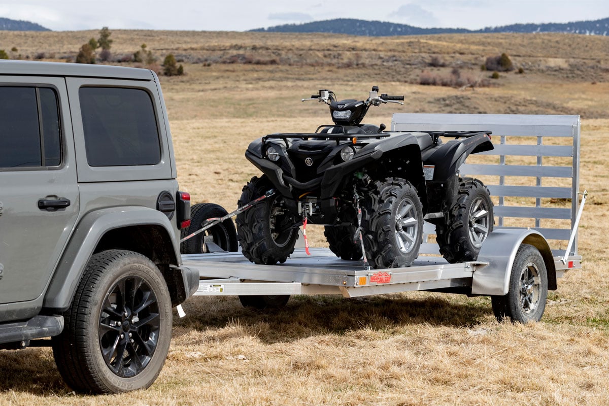 close-up-of-jeep-hauling-high-country-open-utility-ar-2.0-trailers-on-grass-floor