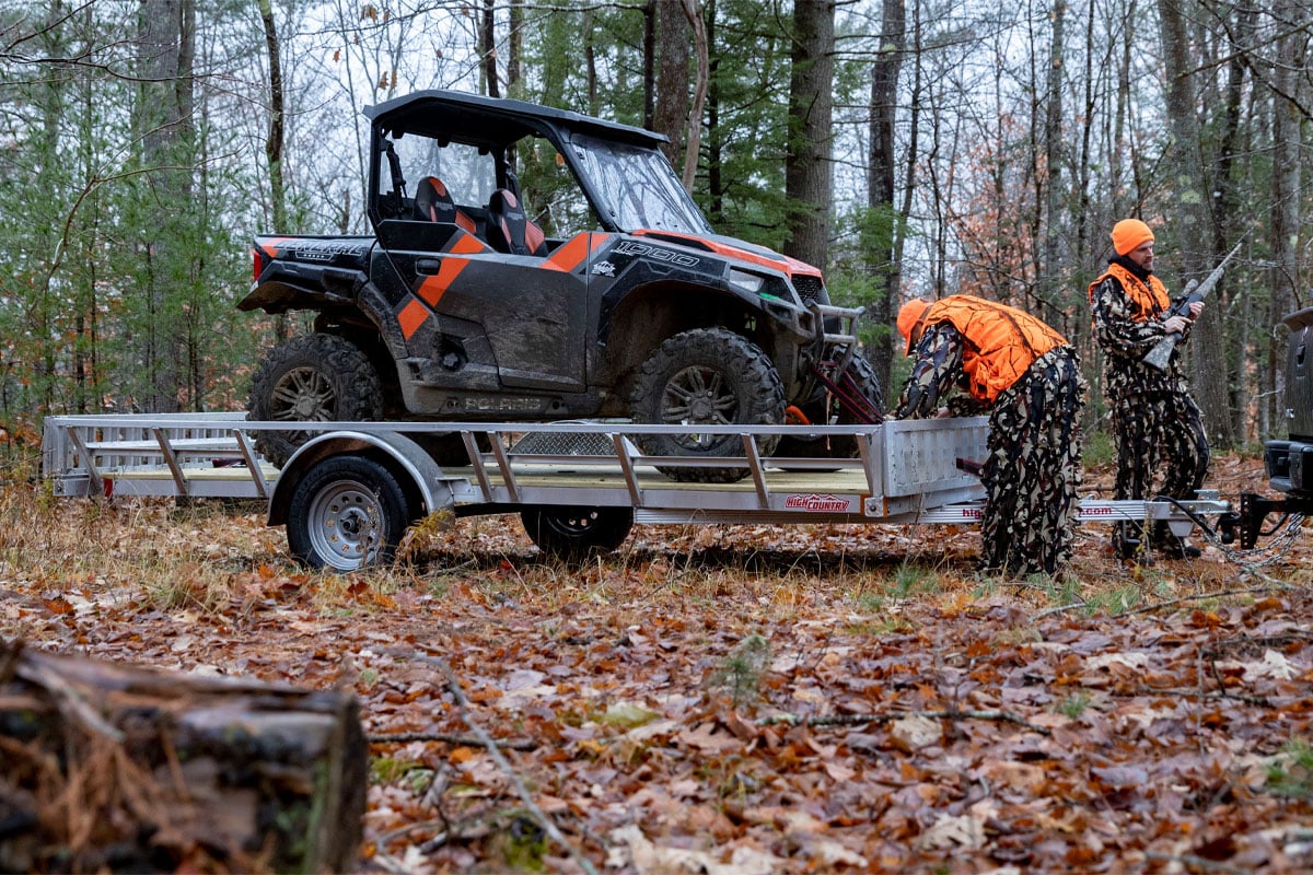 Two People Unloading ATV Off Of 83 Inch Open ATV Trailer In Woods